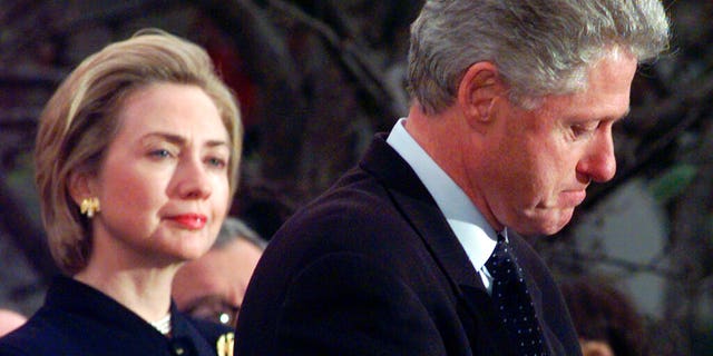 In this Dec. 19, 1998 file photo, first lady Hillary Rodham Clinton watches President Clinton pause as he thanks those Democratic members of the House of Representatives who voted against his impeachment.