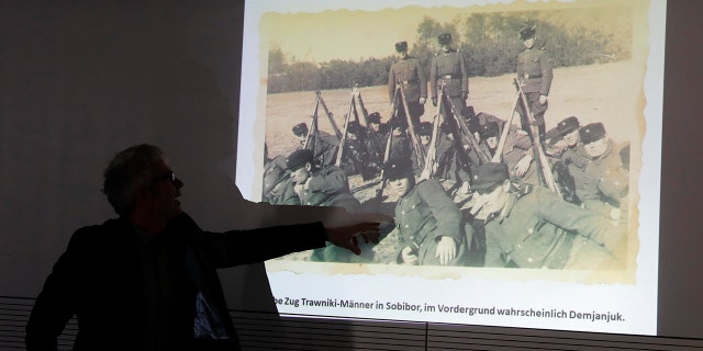 Historican Martin Cueppers points at a man, presumably former security guard John Demjanjuk, at the Nazi death camp Sobibor during a news conference of newly discovered photos from the Sobibor camp in Berlin, Germany, Tuesday, Jan. 28, 2020. (AP Photo/Markus Schreiber)