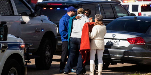 Residents embrace near police and fire cars that surround the scene of a shooting at West Freeway Church of Christ in White Settlement, Texas, Sunday, Dec. 29, 2019. (Yffy Yossifor/Star-Telegram via AP)