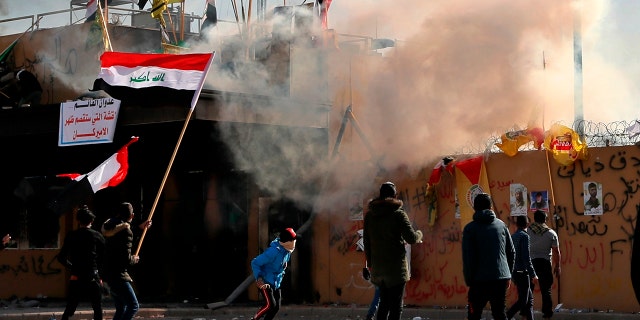 U.S. troops fired tear gas on Wednesday to disperse pro-Iran protesters who were gathered outside the U.S. Embassy compound in Baghdad for a second day as dozens of pro-Iranian militiamen and their supporters had camped out at the gates of the embassy in Baghdad, where they stayed the night. (AP Photo/Khalid Mohammed)