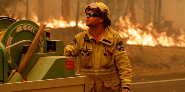 A Forest Corporation worker manages a fire hose as he battles a fire near Moruya, Australia, Saturday, Jan. 4, 2020. 
