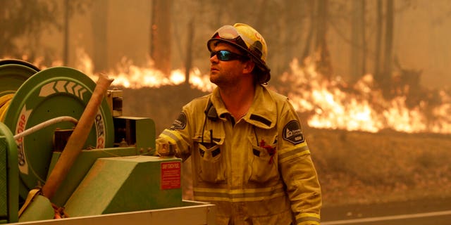 A Forest Corporation worker manages a fire hose as he battles a fire near Moruya, Australia, Saturday, Jan. 4, 2020.