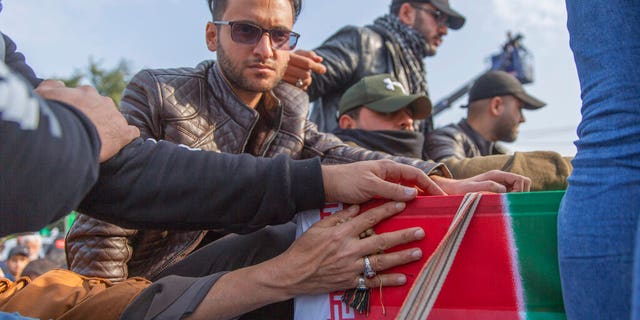 Mourners reach for the coffin during the funeral of Iran's top general Qassem Soleimani in Baghdad, Iraq, Saturday, Jan. 4, 2020.