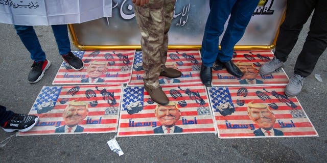 Mourners step over a U.S. flags with pictures of President Trump while waiting for the funeral of Iran's top general Qassem Soleimani and Abu Mahdi al-Muhandis, deputy commander of Iran-backed militias in Iraq known as the Popular Mobilization Forces, in Baghdad, Iraq, Saturday