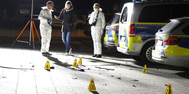 Police officers investigate inside a cordoned-off area in front of a police station in Gelsenkirchen, Germany, late Sunday, Jan. 5, 20120. (Stephan Witte/dpa via AP)