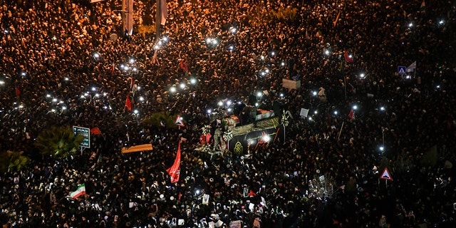 Mourners surround a truck carrying the flag draped coffins of Gen. Qassem Soleimani and his comrades in the holy city of Qom south of the capital Tehran, Iran, Monday, Jan. 6, 2020. (Amir Hesaminejad/Tasnim News Agency via AP)