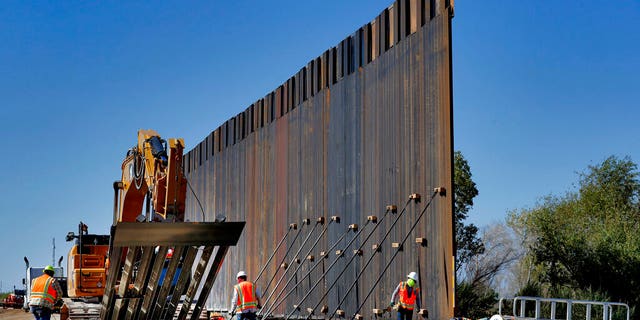 FILE: Government contractors erect a section of Pentagon-funded border wall along the Colorado River in Yuma, Ariz.
