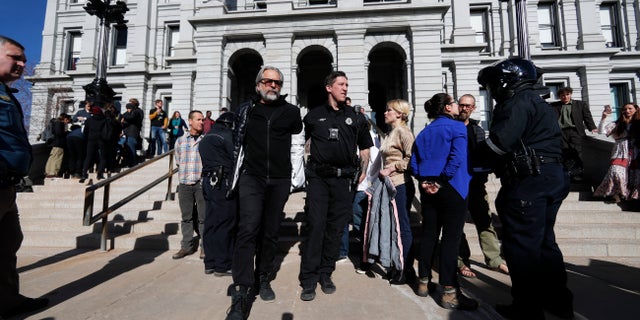 A Denver Police Department officer leads away one of several anti-fracking protesters who interrupted the State of State speech by Colorado Gov. Jared Polis in the State Capitol Thursday, Jan. 9, 2020, in Denver. (AP Photo/David Zalubowski)