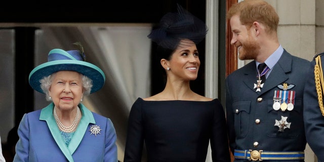 In this Tuesday, July 10, 2018, file photo Britain's Queen Elizabeth II, Meghan the Duchess of Sussex and Prince Harry watch a flypast of Royal Air Force aircraft pass over Buckingham Palace in London. As part of a surprise announcement distancing themselves from the British royal family, Prince Harry and his wife Meghan declared they will “work to become financially independent."