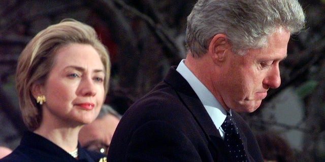 Dans cette photo d'archive du 19 décembre 1998, la première dame Hillary Rodham Clinton regarde le président Clinton faire une pause alors qu'il remercie les membres démocrates de la Chambre des représentants qui ont voté contre la destitution à la Maison Blanche à Washington. 