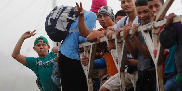 Migrants ride on top of a truck moving along the highway, in hopes of reaching the distant United States, from San Pedro Sula, Honduras, early Wednesday. Hundreds of Honduran migrants started walking and hitching rides Wednesday from the city of San Pedro Sula, in a bid to form the kind of migrant caravan that reached the U.S. border in 2018. (AP Photo/Delmer Martinez)
