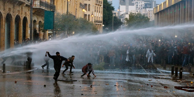 Anti-government demonstrators clash with riot police at a road leading to the parliament building in Beirut, Lebanon, Saturday, Jan. 18, 2020. Riot police fired tears gas and sprayed protesters with water cannons near parliament building to disperse thousands of people after riots broke out during a march against the ruling elite amid a severe economic crisis. (AP Photo/Bilal Hussein)