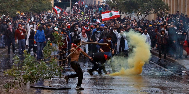 Anti-government demonstrators clash with riot police at a road leading to the parliament building in Beirut, Lebanon, Saturday, Jan. 18, 2020. Riot police fired tears gas and sprayed protesters with water cannons near parliament building to disperse thousands of people after riots broke out during a march against the ruling elite amid a severe economic crisis. (AP Photo/Bilal Hussein)