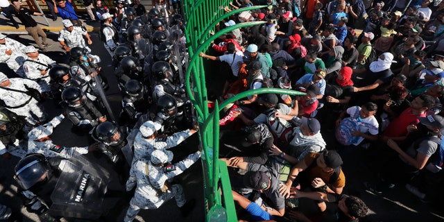 Migrants charge on the Mexican National Guardsmen at the border crossing between Guatemala and Mexico in Tecun Uman, Guatemala, Saturday, Jan. 18, 2020. More than a thousand Central American migrants surged onto the bridge spanning the Suchiate River, that marks the border between both countries, as Mexican security forces attempted to impede their journey north. (AP Photo/Marco Ugarte)
