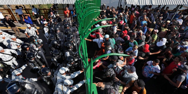 Migrants charge on the Mexican National Guardsmen at the border crossing between Guatemala and Mexico in Tecun Uman, Guatemala, Saturday, Jan. 18, 2020. More than a thousand Central American migrants surged onto the bridge spanning the Suchiate River, that marks the border between both countries, as Mexican security forces attempted to impede their journey north. (AP Photo/Marco Ugarte)