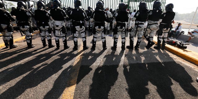 Mexican National Guardsmen block the border crossing between Guatemala and Mexico in Tecun Uman, Guatemala, Saturday, Jan. 18, 2020. More than a thousand Central American migrants surged onto the bridge spanning the Suchiate River, that marks the border between both countries, as Mexican security forces attempted to impede their journey north. (AP Photo/Marco Ugarte)