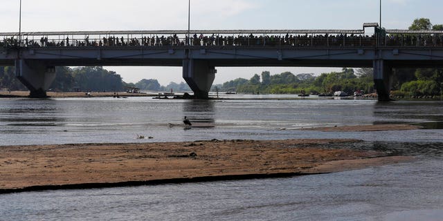 Migrants crowd the the bridge spanning the Suchiate River on the border between Guatemala and Mexico in Ciudad Hidalgo, Saturday, Jan. 18, 2020. More than a thousand Central American migrants surged onto the bridge as Mexican National Guardsmen attempted to impede their journey north. (AP Photo/Marco Ugarte)