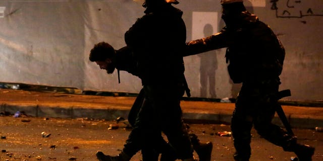 Lebanese police arrest an anti-government protester after dispersing a protest in Beirut, Lebanon, Saturday, Jan. 18, 2020. 