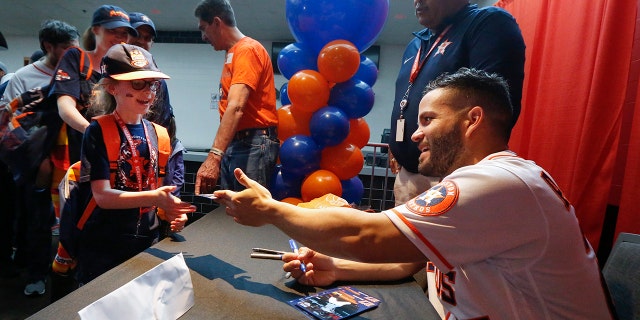 Jose Altuve signs autographs for young fans during the baseball team's FanFest at Minute Maid Park on Saturday, Jan. 18, 2020, in Houston. (Associated Press)