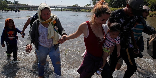 Central American migrants cross the Suchiate River by foot from Tecun Uman, Guatemala, to Mexico, on Monday. More than a thousand Central American migrants hoping to reach the United States marooned in Guatemala are walking en masse across a river leading to Mexico in an attempt to convince authorities there to allow them passage through the country. (AP Photo/Moises Castillo)