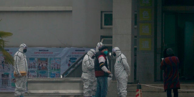 Staff in biohazard suits hold a metal stretcher by the in-patient department of Wuhan Medical Treatment Center, where some infected with a novel coronavirus are being treated, in Wuhan, China, on Tuesday. Heightened precautions were being taken in China and elsewhere Tuesday as governments strove to control the outbreak of the coronavirus, which threatens to grow during the Lunar New Year travel rush. (AP Photo/Dake Kang)
