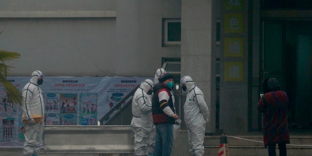 Staff in biohazard suits hold a metal stretcher by the in-patient department of Wuhan Medical Treatment Center, where some infected with a novel coronavirus are being treated, in Wuhan, China, on Tuesday. Heightened precautions were being taken in China and elsewhere Tuesday as governments strove to control the outbreak of the coronavirus, which threatens to grow during the Lunar New Year travel rush. (AP Photo/Dake Kang)