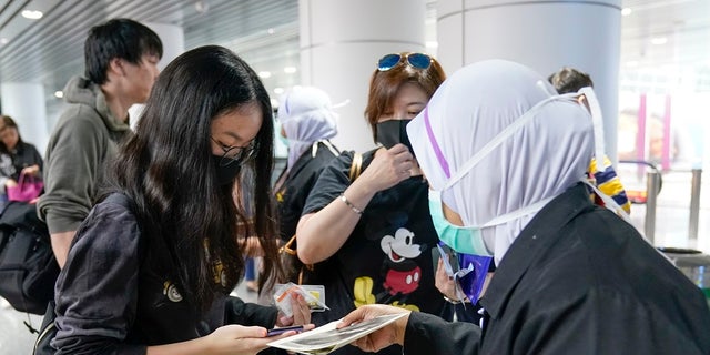 Health officials hand out information about the current coronavirus at Kuala Lumpur International Airport in Sepang, Malaysia. Countries both in the Asia-Pacific and elsewhere have initiated body temperature checks at airports, railway stations and along highways in hopes of catching those at risk of carrying a new coronavirus that has sickened more than 200 people in China. (AP Photo/Vincent Thian)