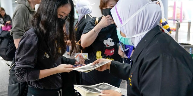 Health officials hand out information about the current coronavirus at Kuala Lumpur International Airport in Sepang, Malaysia. Countries both in the Asia-Pacific and elsewhere have initiated body temperature checks at airports, railway stations and along highways in hopes of catching those at risk of carrying a new coronavirus that has sickened more than 200 people in China. (AP Photo/Vincent Thian)