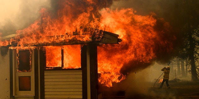 Jan. 23, 2020: A firefighter battles the Morton Fire as it consumes a home near Bundanoon, New South Wales, Australia. (AP Photo/Noah Berger)