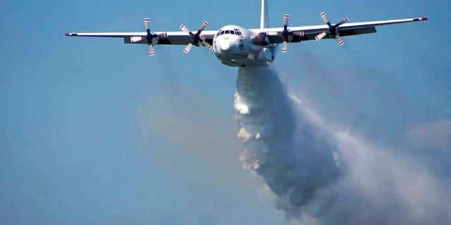 In this undated photo released from the Rural Fire Service, a C-130 Hercules plane called "Thor" drops water during a flight in Australia. Officials in Australia on Thursday, Jan. 23, 2020, searched for a water tanker plane feared to have crashed while fighting wildfires. (RFS via AP)
