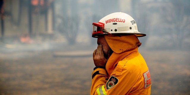 A firefighter covers his face while battling the Morton Fire near Bundanoon, New South Wales, Australia, on Thursday, Jan. 23, 2020. (AP Photo (AP Photo/Noah Berger)