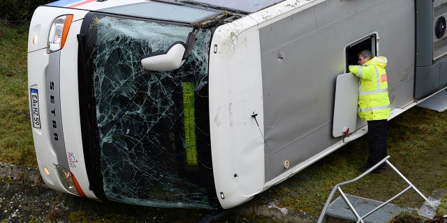 A police officer looks into a school bus that has crashed in Berka Vor Dem Hainich, near Eisenach, Germany, Thursday, Jan. 23, 2020. (Swen Pfoertner/dpa via AP)