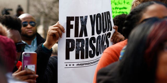Several attendees waved posters calling for the state to "Fix your prisons," at a rally in front of the Mississippi Capitol in Jackson.