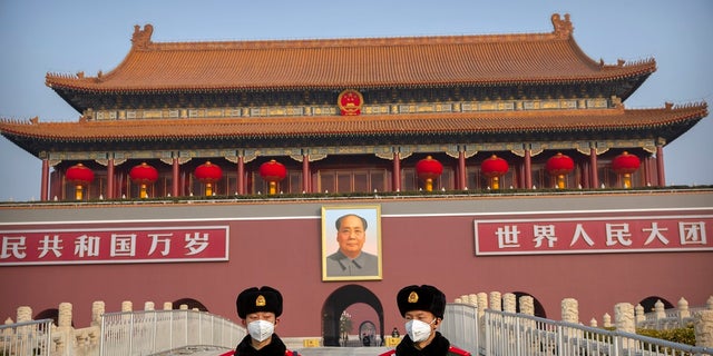 Paramilitary police wear face masks as they stand guard at Tiananmen Gate in Beijing. (AP Photo/Mark Schiefelbein)