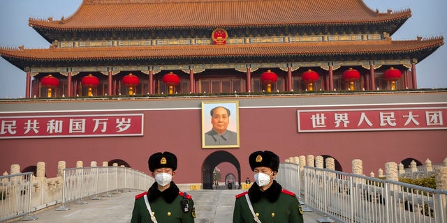 Paramilitary police wear face masks as they stand guard at Tiananmen Gate in Beijing. (AP Photo/Mark Schiefelbein)