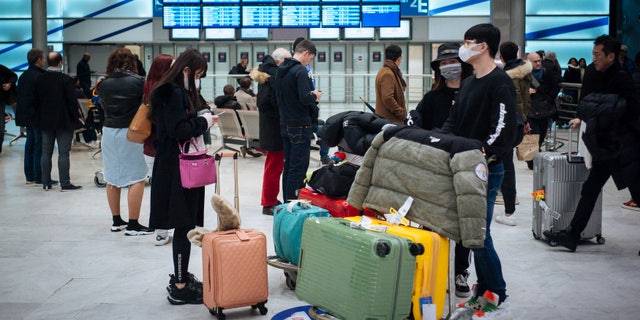 Travelers from Beijing, wearing masks, arrive at Charles de Gaulle airport, north of Paris, early Monday, Jan. 27, 2020. (AP Photo/Kamil Zihnioglu)