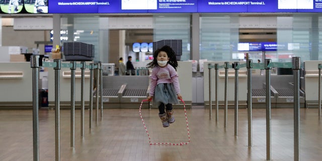 A girl wearing a mask skips rope at Incheon International Airport in Incheon, South Korea, Monday, Jan. 27, 2020. (AP Photo/Ahn Young-joon)