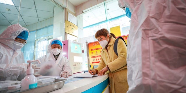 Medical workers in protective gear talk with a woman suspected of being ill with a coronavirus at a community health station in Wuhan in central China's Hubei Province on Monday. (Chinatopix via AP)