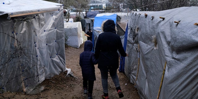 Migrants walk between makeshift tents outside the perimeter of the overcrowded Moria refugee camp after a rainfall on the northeastern Aegean island of Lesbos, Greece, Tuesday, Jan.28, 2020.