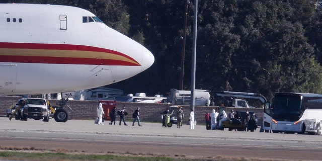 Passengers board buses after arriving on an airplane carrying U.S. citizens being evacuated from Wuhan, China, at March Air Reserve Base in Riverside, Calif. Jan. 29, 2020. The passengers will undergo additional screenings in California and be placed in temporary housing. Officials have not said how long they will stay there. (AP Photo/Ringo H.W. Chiu)