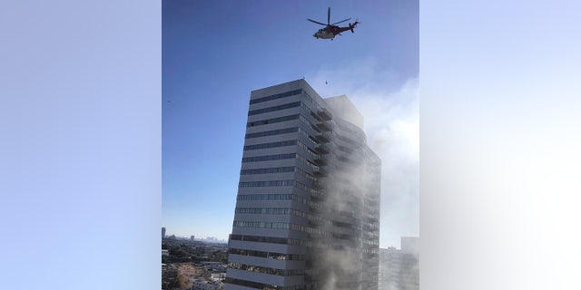 Firefighters swarmed the building on the city's west side and people could be seen on the roof as flames and smoke rose from the sixth floor. (Megan Feldman via AP)
