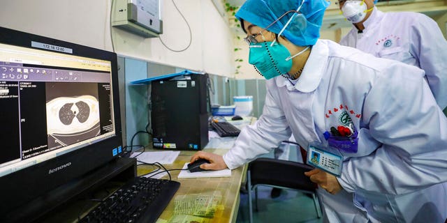 Doctors look at a CT scan of a patient at a hospital in Wuhan in central China's Hubei Province, Thursday, Jan. 30, 2020. 