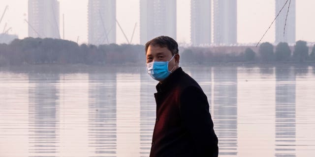 A man wears a face mask as he stands along the waterfront in Wuhan in central China's Hubei Province, Thursday, Jan. 30, 2020. 