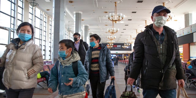 Travelers wear face masks as they prepare to board a train at the Beijing Railway Station in Beijing, Friday, Jan. 31, 2020.  (AP Photo/Mark Schiefelbein)