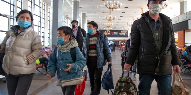 Travelers wear face masks as they prepare to board a train at the Beijing Railway Station in Beijing, Friday, Jan. 31, 2020.  (AP Photo/Mark Schiefelbein)