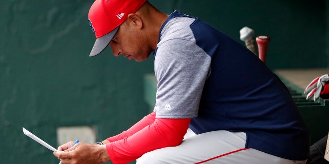FILE - In this March 20, 2019, file photo, Boston Red Sox manager Alex Cora looks over the lineup before the team's spring training baseball game against the Baltimore Orioles in Sarasota, Fla. Cora was fired by the Red Sox on Tuesday, Jan. 14, 2020, a day after baseball Commissioner Rob Manfred implicated him in the sport's sign-stealing scandal. (AP Photo/John Bazemore)