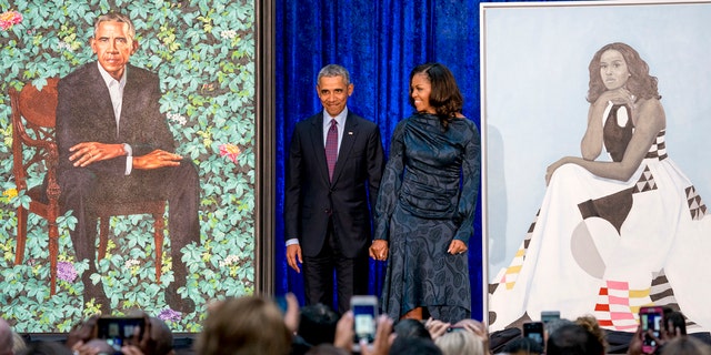 Former President Obama and former first lady Michelle Obama stand on stage together as their official portraits are unveiled at a ceremony at the Smithsonian's National Portrait Gallery in Washington, DC