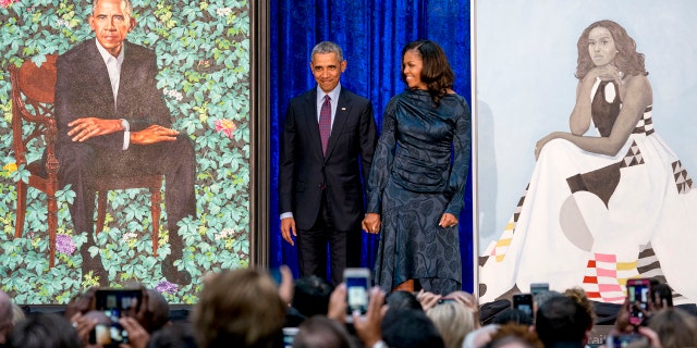 Former President Obama and former first lady Michelle Obama stand on stage together as their official portraits are unveiled at a ceremony at the Smithsonian's National Portrait Gallery in Washington, D.C.