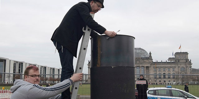 The author Eliyah Havemann reattaching a previously dismantled steel plate to the controversial steel column opposite the Reichstag building in Berlin on Sunday. (Paul Zinken/dpa via AP)