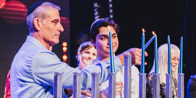 Birthright Israel CEO Gidi Mark lights the Hannukah menorah with participants at the 20th anniversary Hannukah kick-off event in Israel.